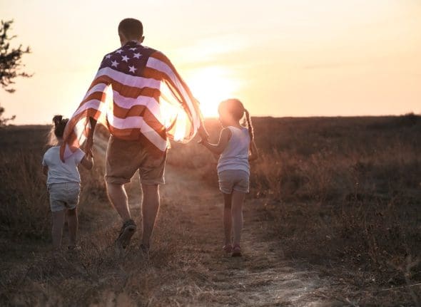 A happy family with an American flag at sunset.